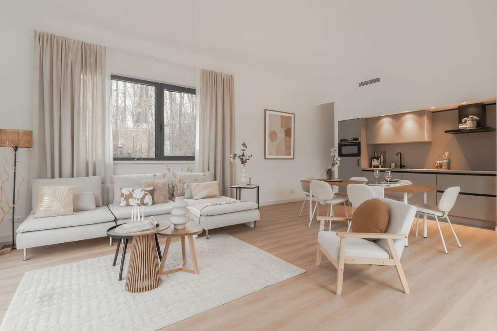 Lichte woonkamer met zithoek, eettafel en open keuken.