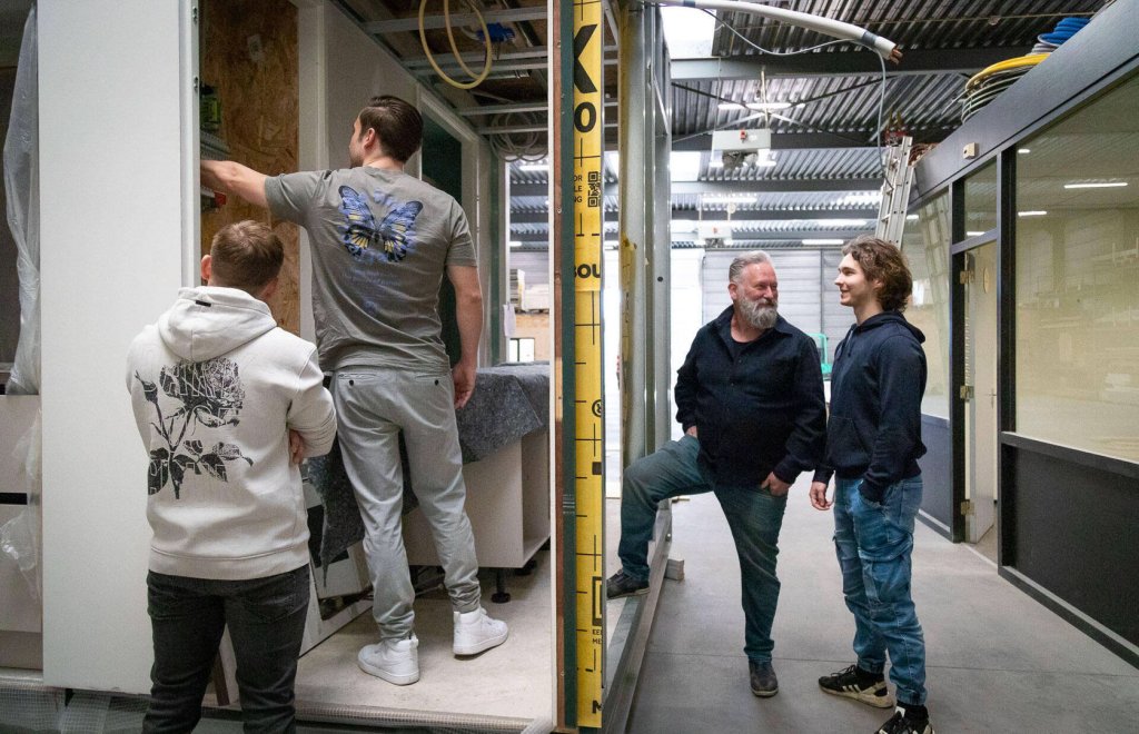 Bezoekers krijgen uitleg bij een woning in de productiehal.
